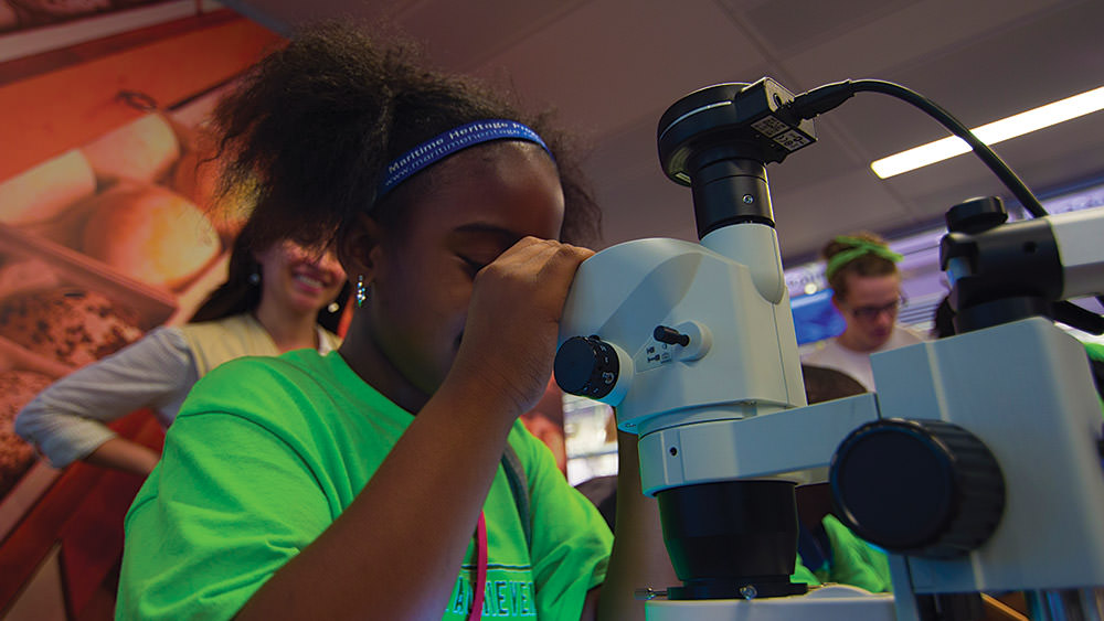 girl looking through a microscope