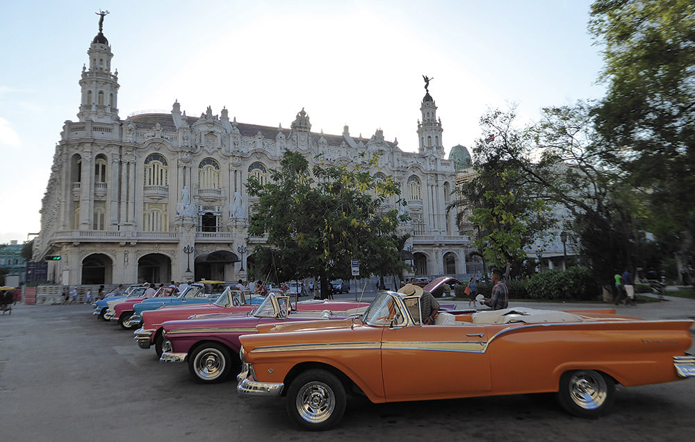 view of cars lined up infront of a building in downtown havana, cuba