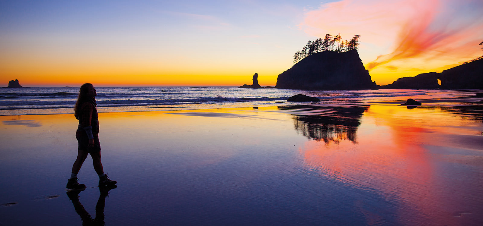women walking on the beach in olympic coast while the sun is setting