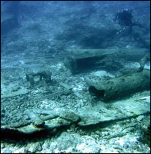NOAA diver above some of the large steel mast sections which lie broken on the seafloor.  