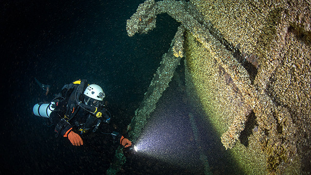 diver shining light on a shipwreck
