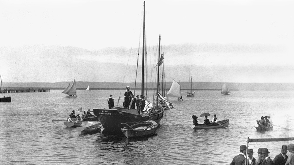 black and white photo of a sailboat on the water surrounded by some smaller boats