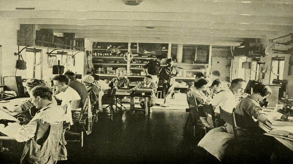 people sitting in two rows at desks with microscopes and other scientific equipment