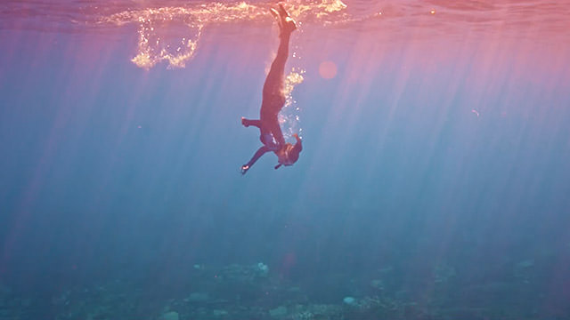 free diver breaking the surface of the water as she dives