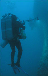 Diver beaming light on shipwreck