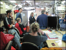 The science party holds a meeting before starting operations to discuss goals of the mission, logistics, and roles.  Chief Scientist Mary Yoklavich (standing, in black) is in charge of the science operations.  
