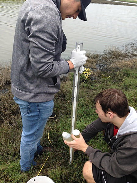 two snapshot day volunteers check water clarity using a transparency tube