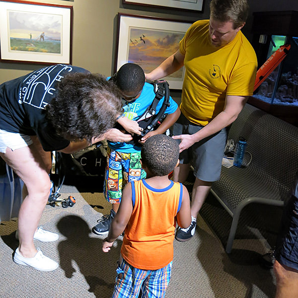 volunteers assiting kid with putting on dive gear