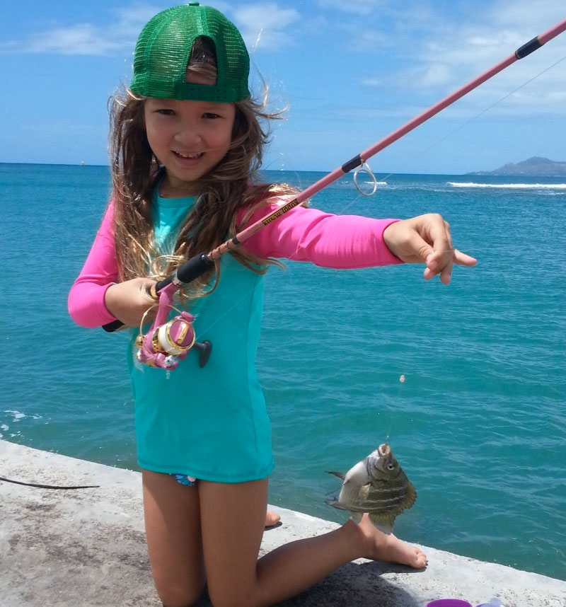 little girl holding up a fish she caught