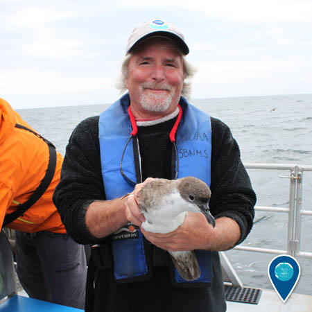 researcher david wiley holding a seabird aboard a ship