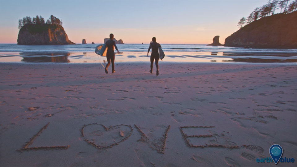 photo of a beach with people looking at the sunset with the words love written in sand