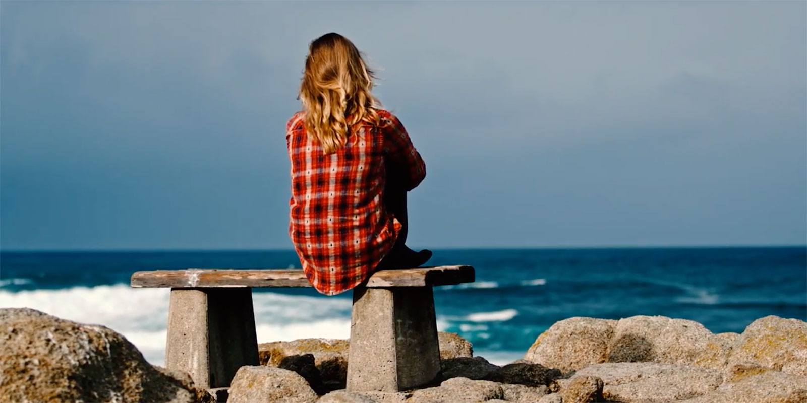 woman sitting on a bench looking at the ocean