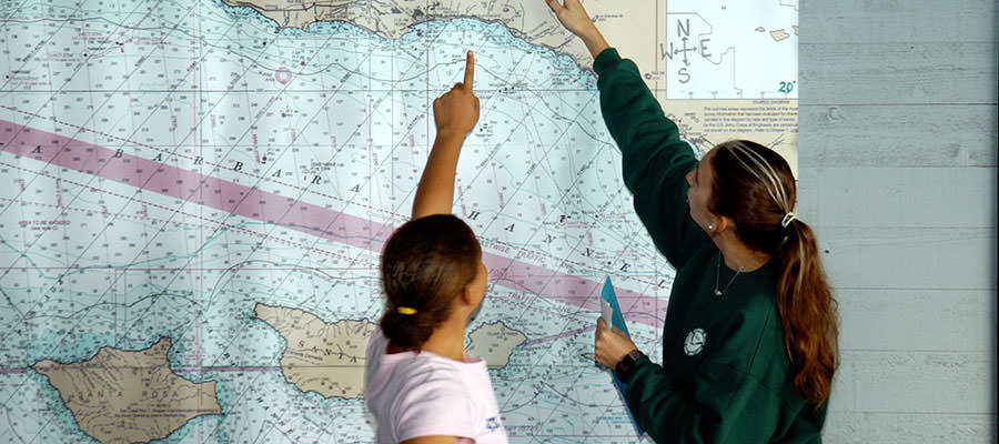 photo of a student and a teacher pointing on a map