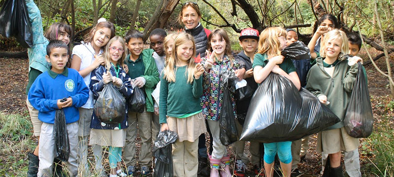 picture of children and teacher holding bags of trash
