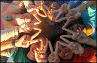kids lying on their backs forming peace sign with there fingers