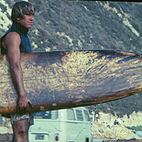 surfer carrying a surfboard covered in oil