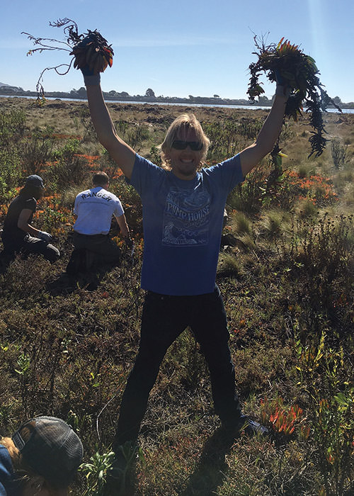 volunteer holds up non-native species he removed during a clean up