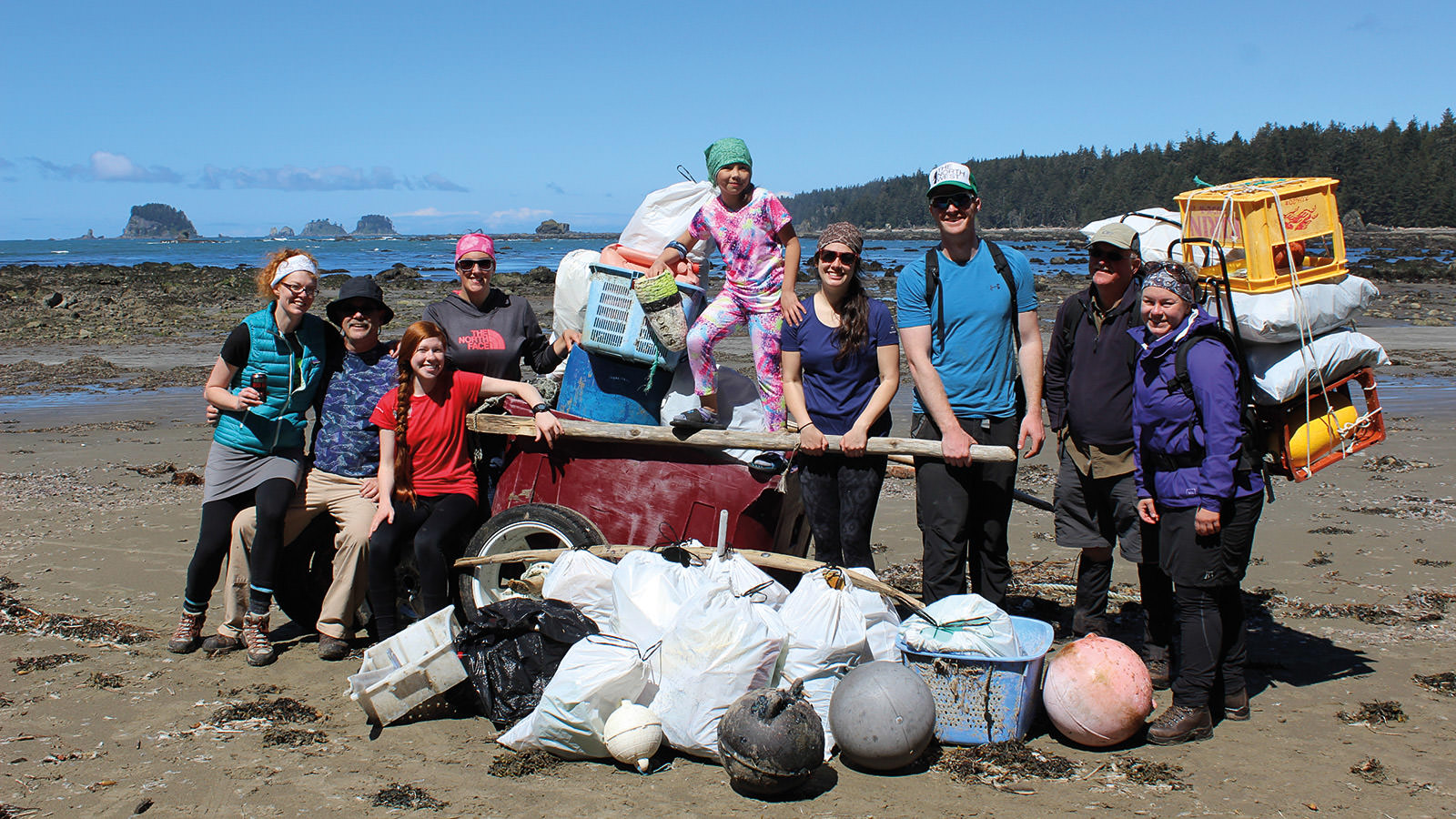 volunteers pose for a picture next to the trash they cleaned up from the beach