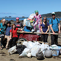 volunteers pose for a picture next to the trash they cleaned up from the beach