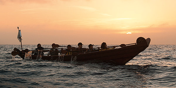 members of the chumash community canoeing across the channel islands harbor in a traditional plank canoe
