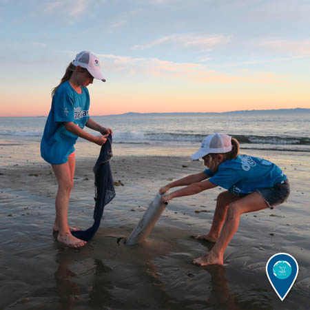 two kids cleaning up marine debris from the beach