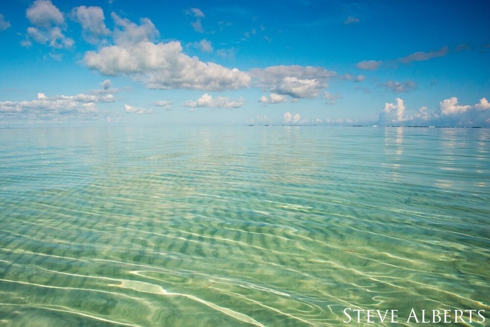 Sand ripples and blue-green waters view.