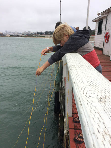 child dangles a string to catch a crab