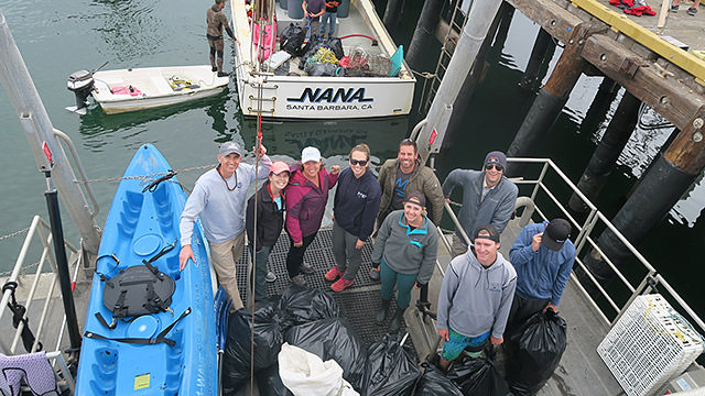 group of men and women standing with full trash bags in santa barbara harbor