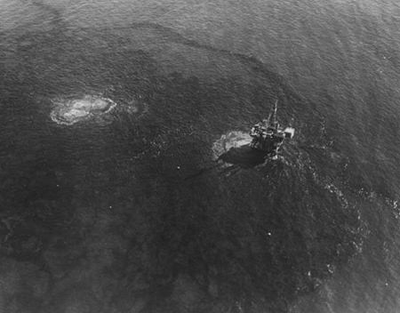 black-and-white aerial view of an oil spill around an oil platform