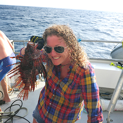 woman on a boat holding a lionfish