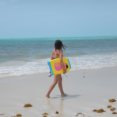 young woman on a beach with a boogie board