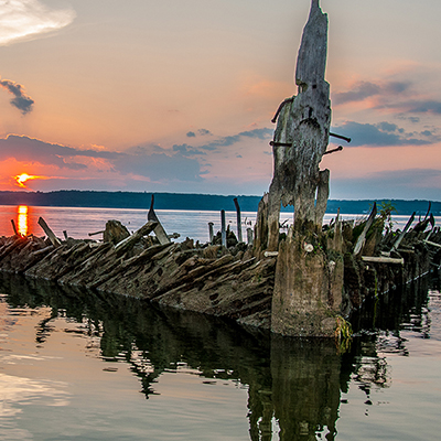 wooden shipwreck above the waterline at sunset
