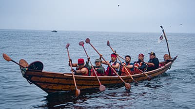 members of the chumash on the water in a tomol(canoe)