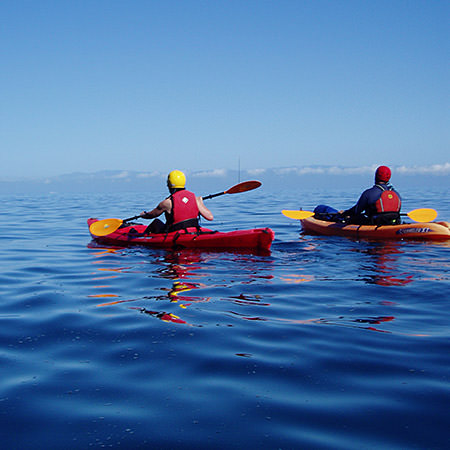 two kayakers paddling out to sea