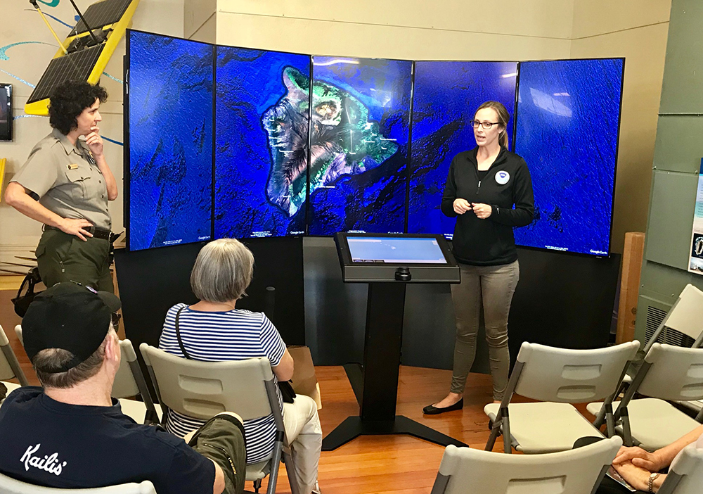 a ranger and a noaa representative present to a group of people