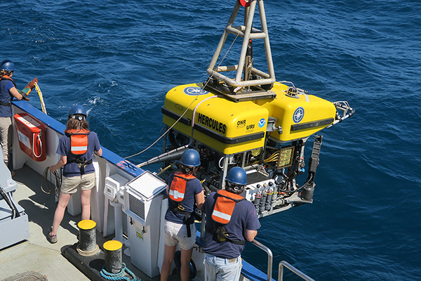 a team of scientists lowering a device into the water