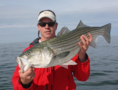 man holding a striped bass he caught