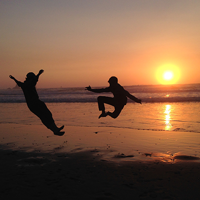 people jumping on beach at sunset