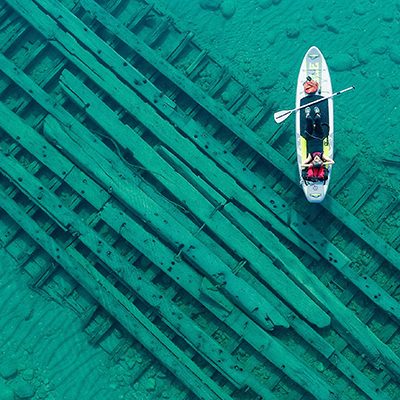 paddleboarder lying down over shipwreck
