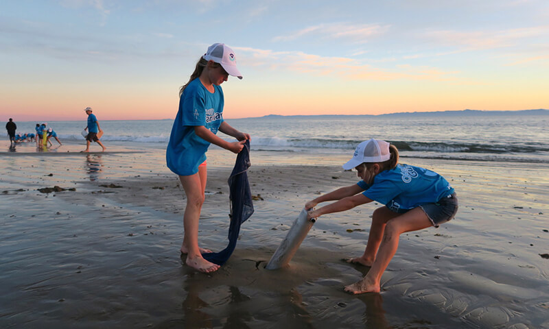 Two children cleaning up a beach
