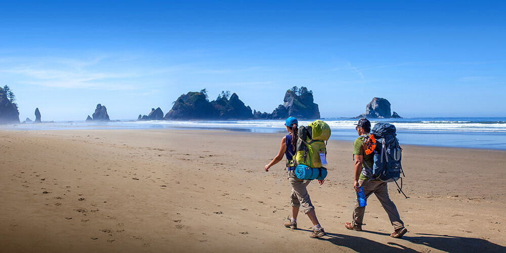 Two backpackers walking on a beach