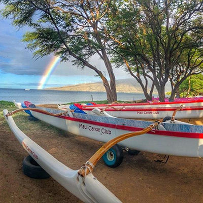 outrigger canoes under a rainbow