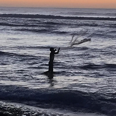 fisherman casting at sunset