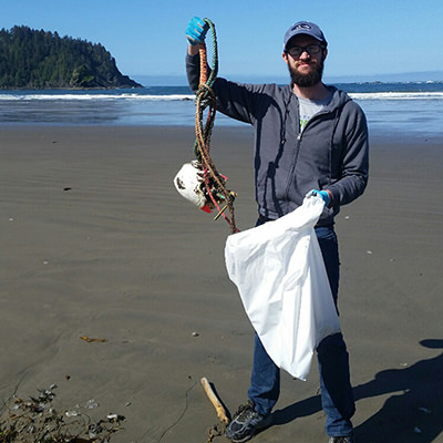 person holding marine debris on a beach