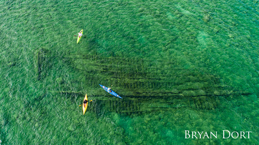 Aerial video of three kayaks over a submerged wreck.