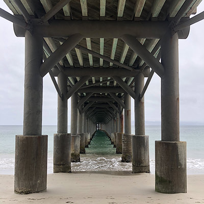 view of the underside of a pier stretching into the ocean