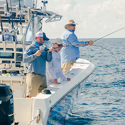 three people fish off the side of a boat