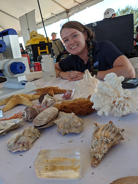erin arneson with a table of shells and other biological artifacts