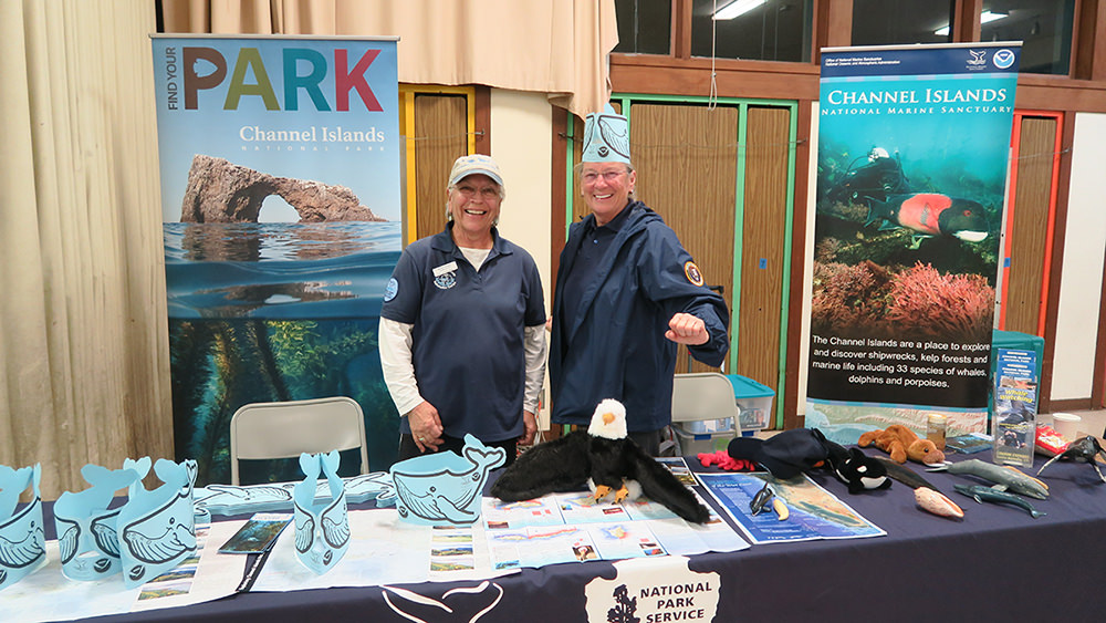 two volunteers at a booth with channel islands national marine sanctuary and national park signage