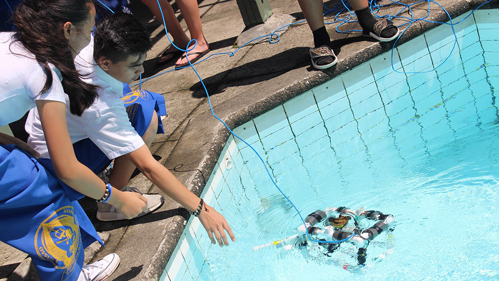 two kids launching an ROV in a pool